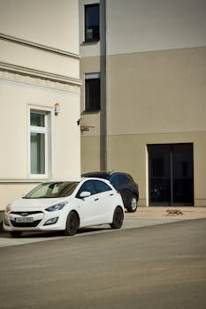 White sedan parked next to a modern building with minimalistic architecture on a sunny day.