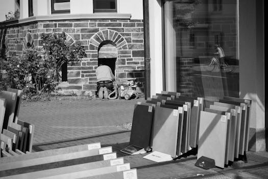 A worker in an urban setting fixes a building frontage in black and white.