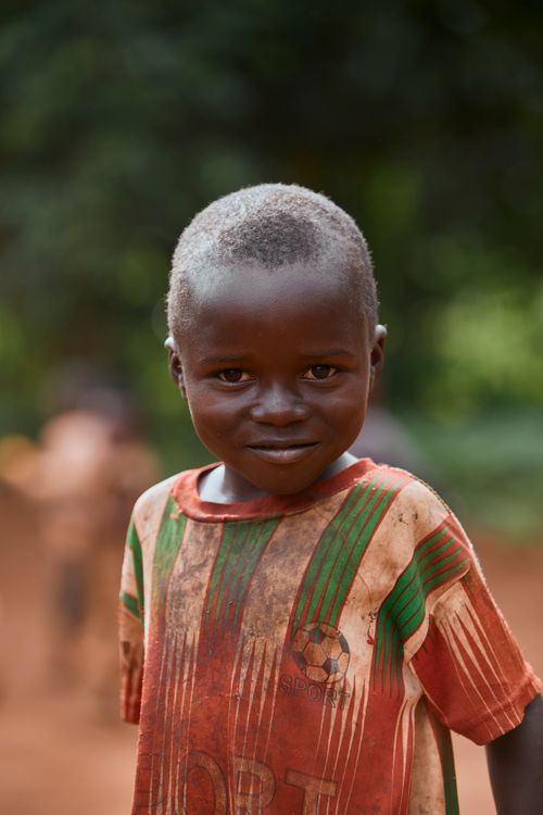 Free A young child smiling outdoors, wearing a colorful striped shirt with a blurred background. Stock Photo