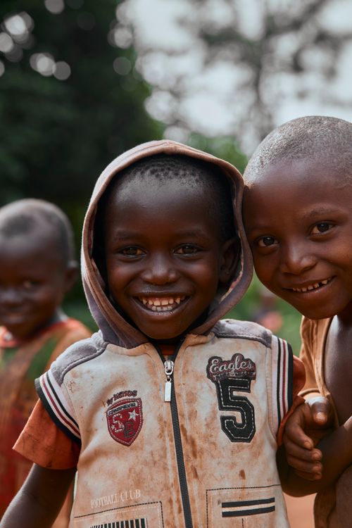 Free Three smiling African children playfully pose for the camera outdoors, showcasing joy and friendship. Stock Photo