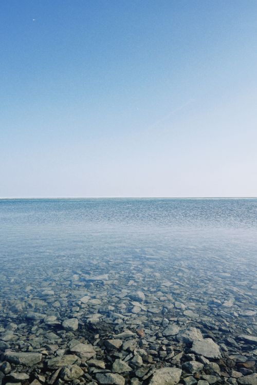 Free Tranquil view of a rocky shoreline and clear blue sky, perfect for nature and travel themes. Stock Photo