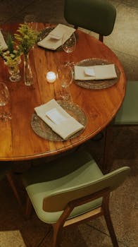 A beautifully arranged round table set for dinner with candles, flowers, and formal place settings.