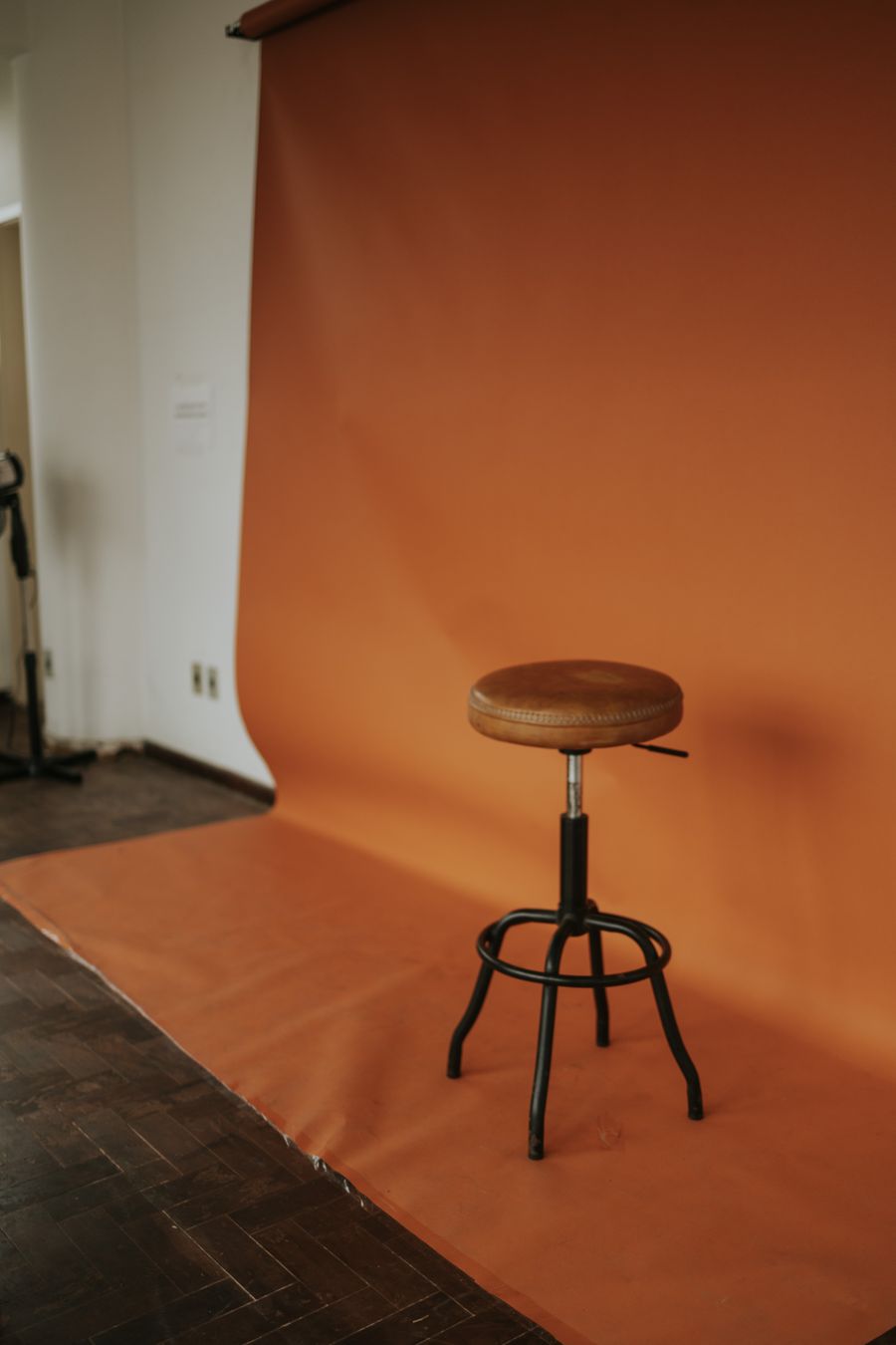 Wooden stool on an orange studio sweep — photo by Letícia Alvares on Pexels