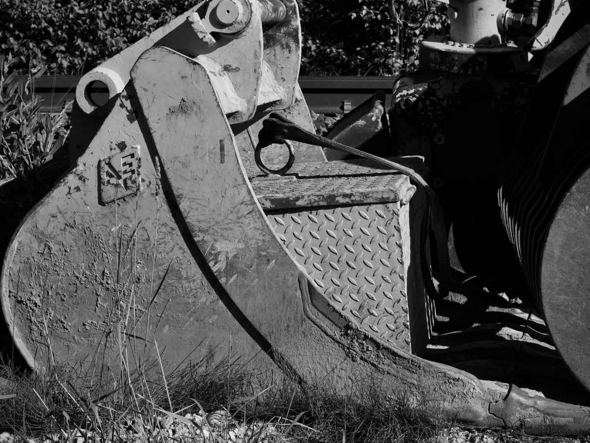 Black and white close-up of an excavator bucket.