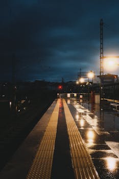 A moody train station in İstanbul at night, reflecting lights on wet surfaces.