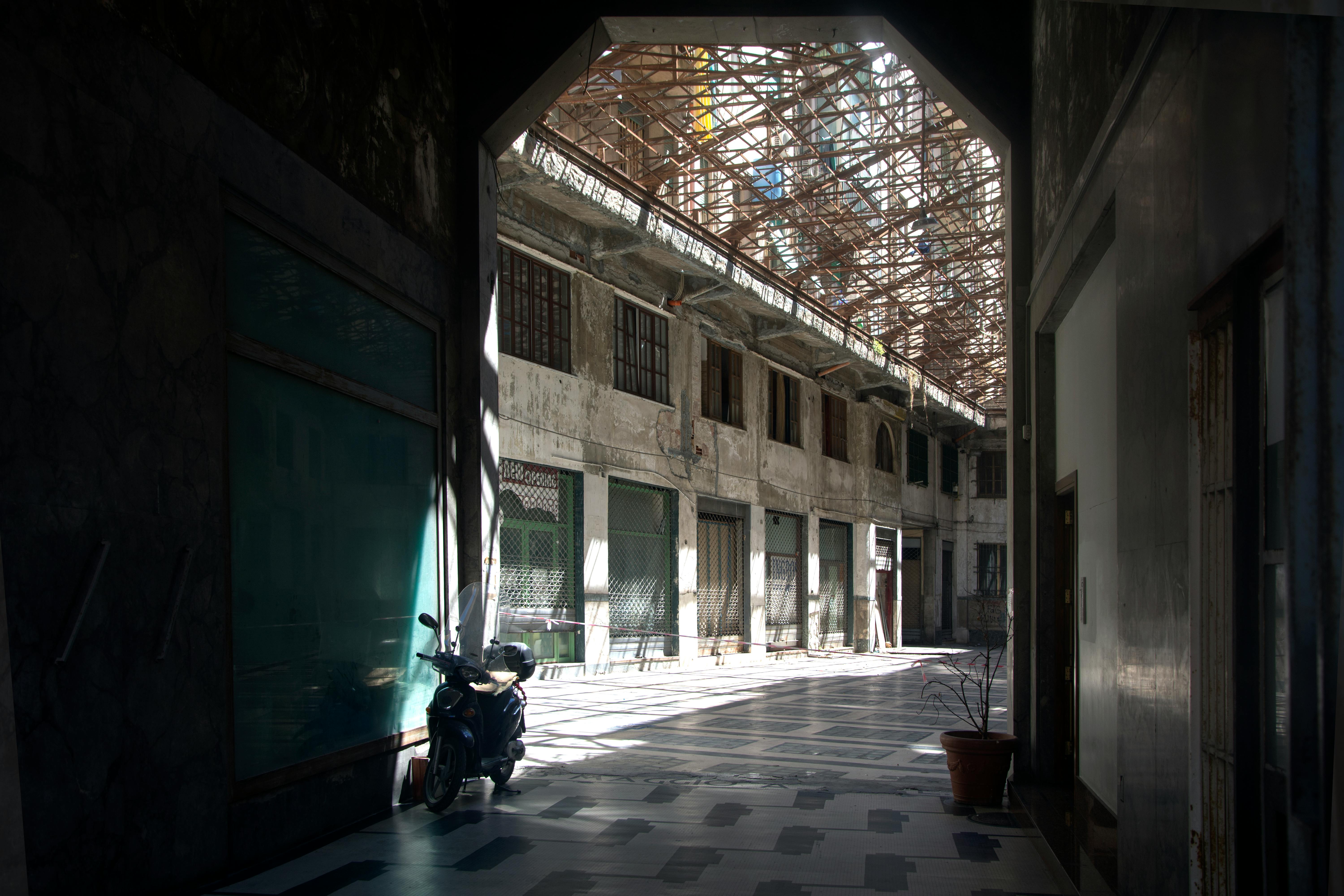 Δωρεάν Ένα σκούτερ παρκαρισμένο σε ένα ηλιόλουστο σοκάκι ενός εγκαταλελειμμένου κτιρίου με ρουστίκ βιομηχανικό σχεδιασμό. Φωτογραφία από στοκ φωτογραφιών