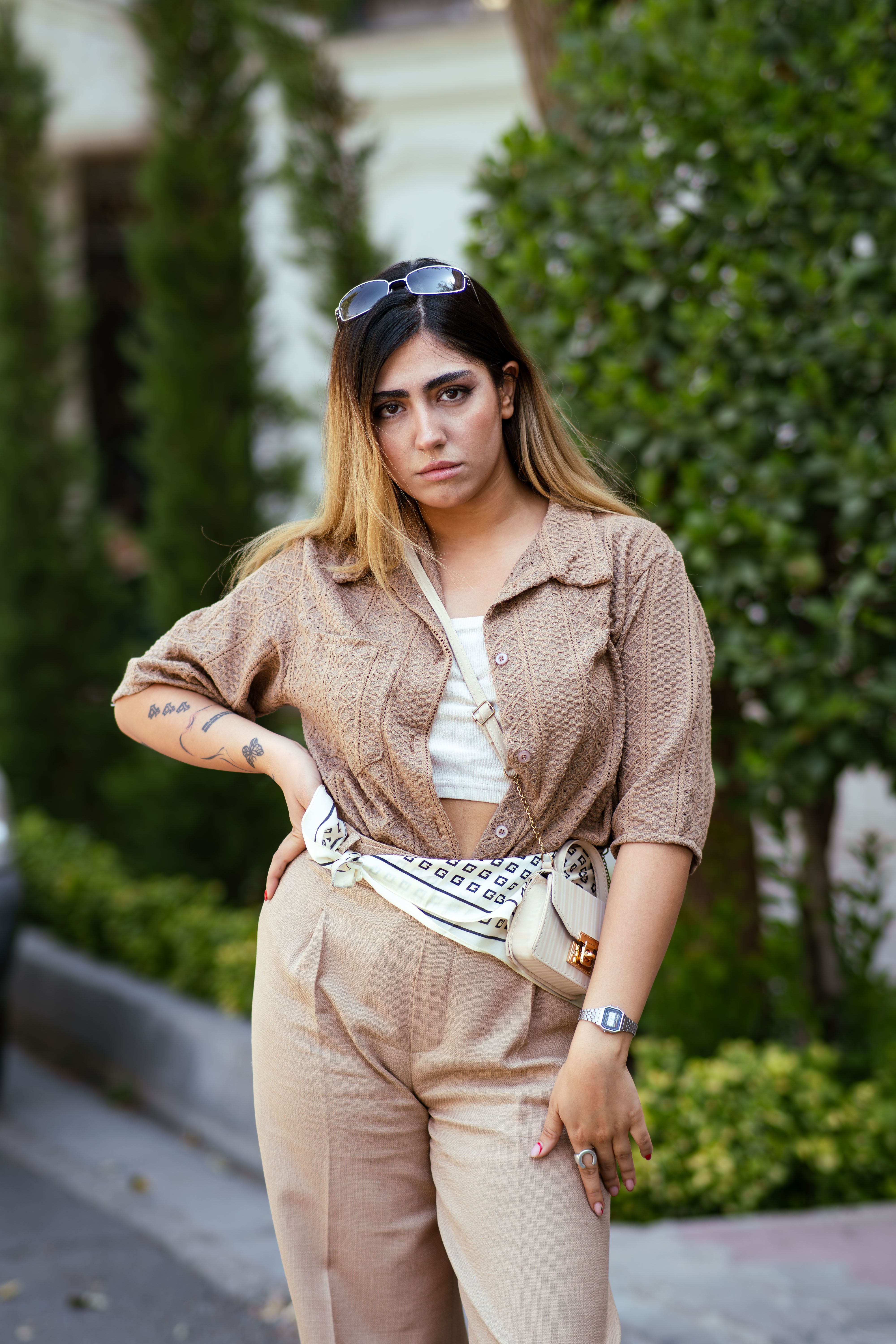 A stylish woman posing confidently outdoors in Tehran, showcasing modern fashion with a neutral palette.