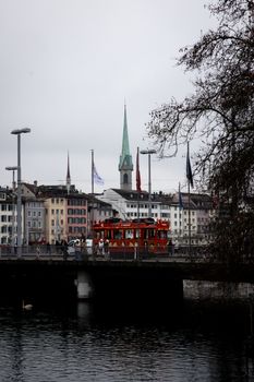 Red tram crossing a bridge in Zürich, showcasing the city's iconic architecture and winter ambiance.