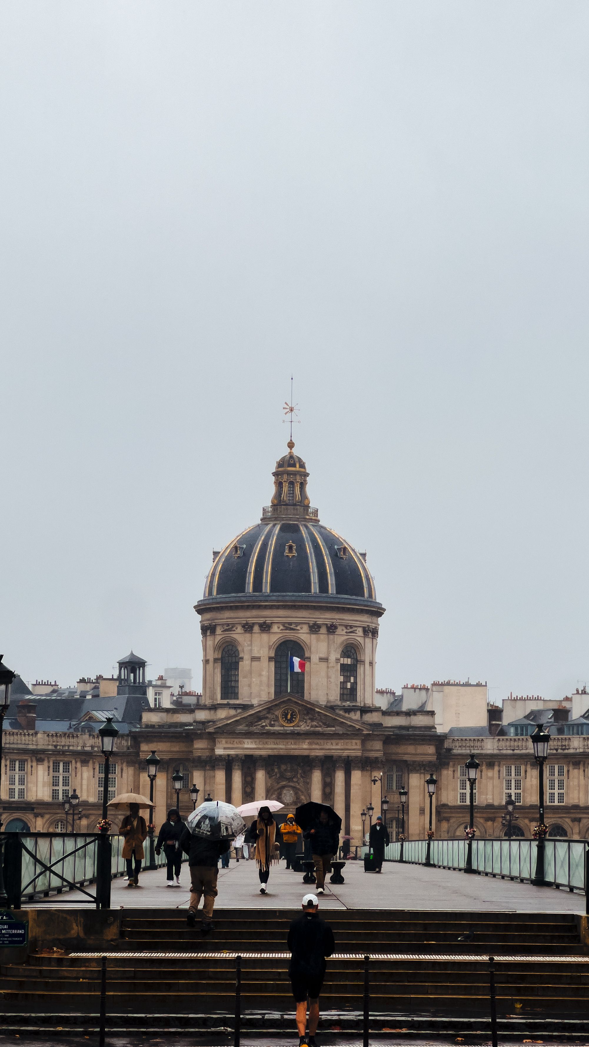 Iconic view of the Institut de France from Pont des Arts on a rainy day in Paris.