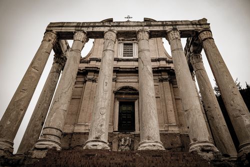 Free A striking view of ancient Roman temple ruins with towering columns in sepia tone. Stock Photo