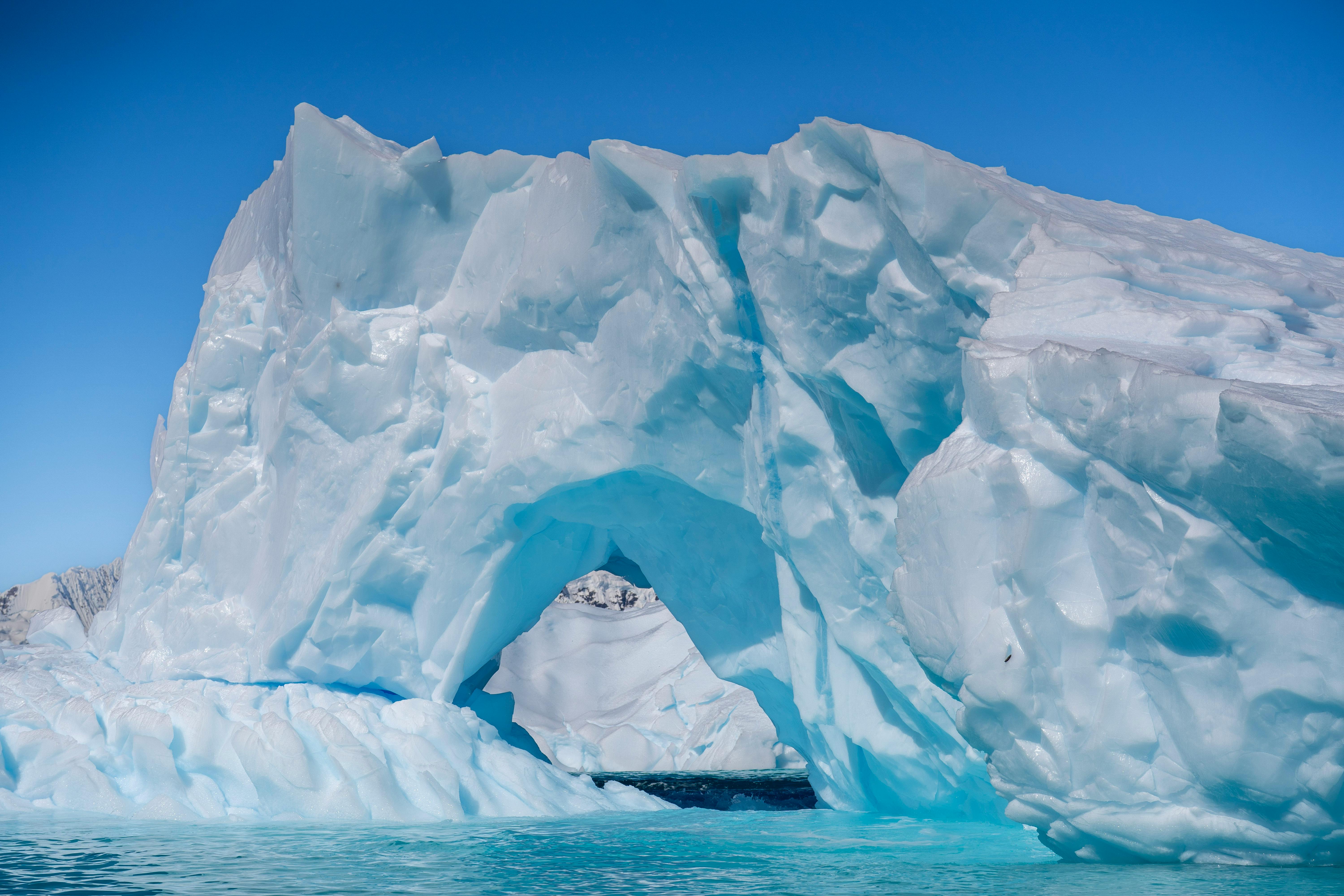 Gratis Gunung es yang menakjubkan dengan formasi lengkungan alami di Antartika, di bawah langit biru yang jernih. Foto Stok