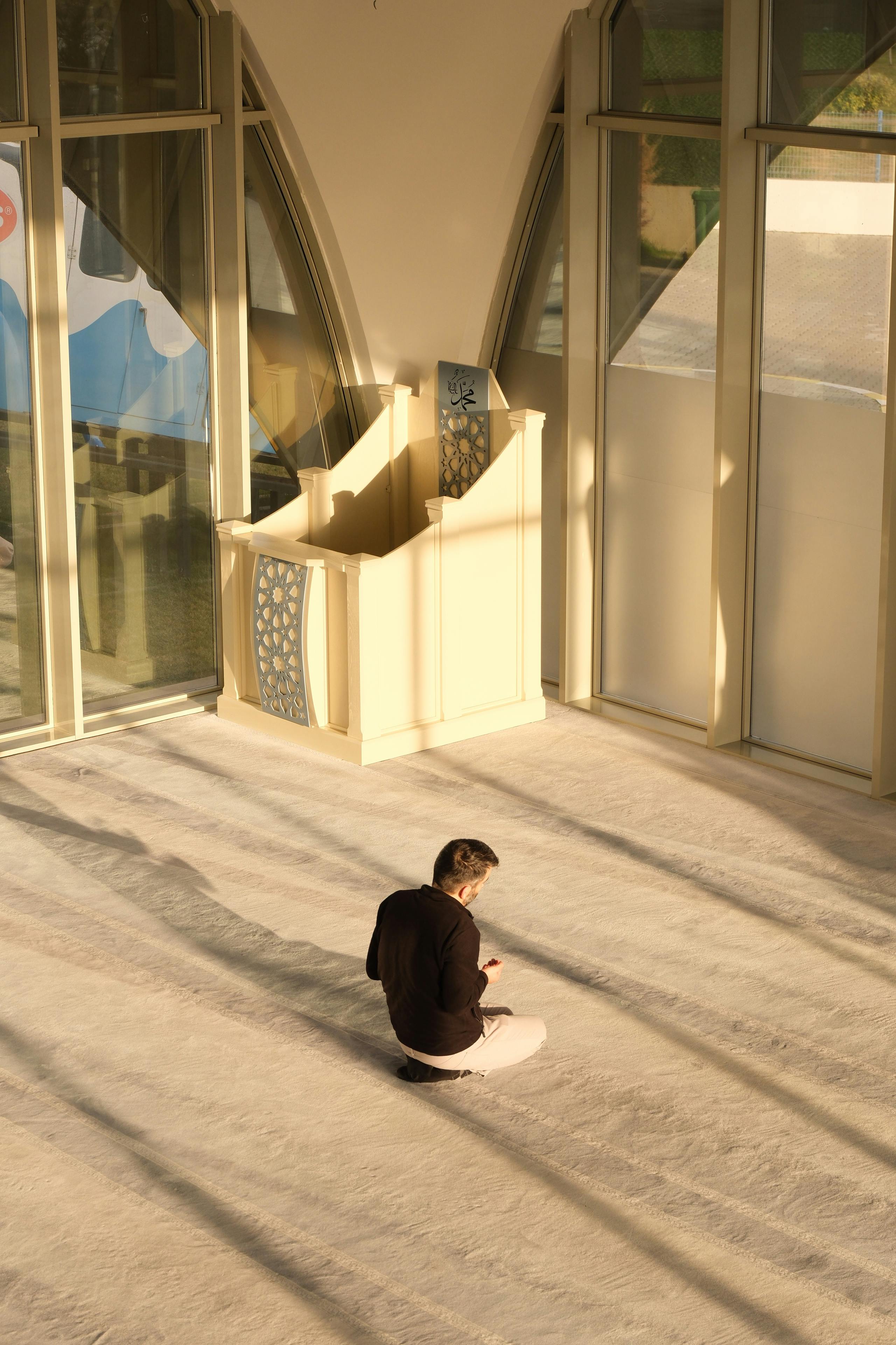 Gratuit Un bărbat se roagă singur într-o cameră însorită a unei moschei, exprimând reflecție spirituală. Fotografie de stoc
