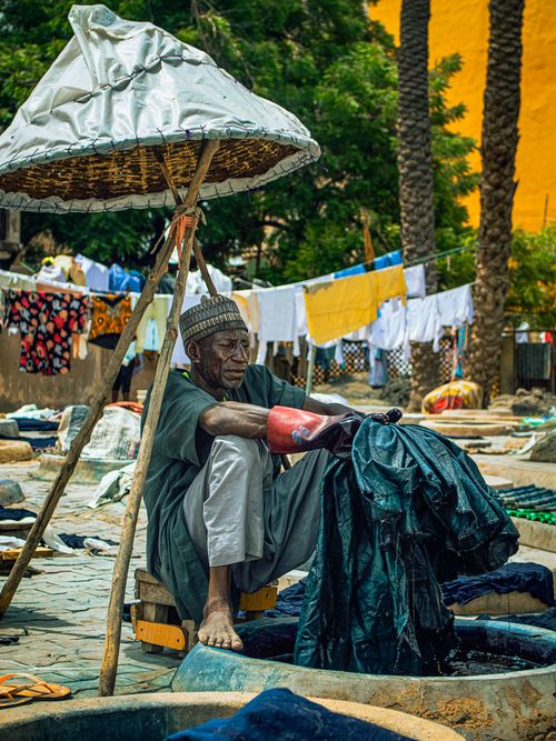 Free An artisan skillfully dyes fabric in an outdoor African market. Stock Photo