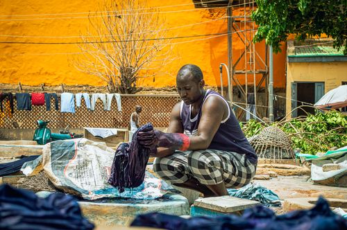 Free A man washes clothes outdoors, adding realism to a vibrant urban scene. Stock Photo