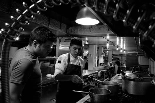 Chefs working attentively in a restaurant kitchen, collaborating over stove preparations.