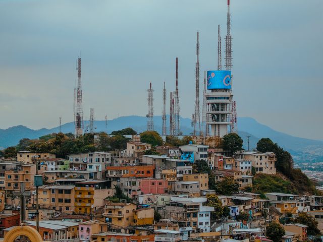 A vibrant view of Guayaquil's skyline with telecommunication towers over colorful hillside houses in Ecuador.