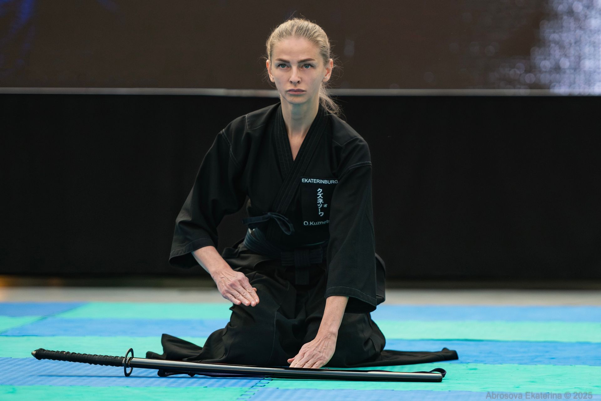 Martial artist in a black gi practicing Iaido sword drawing
