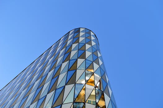 在瑞典哈加伦德，一座现代建筑矗立在清澈的蓝天下，拥有几何玻璃立面