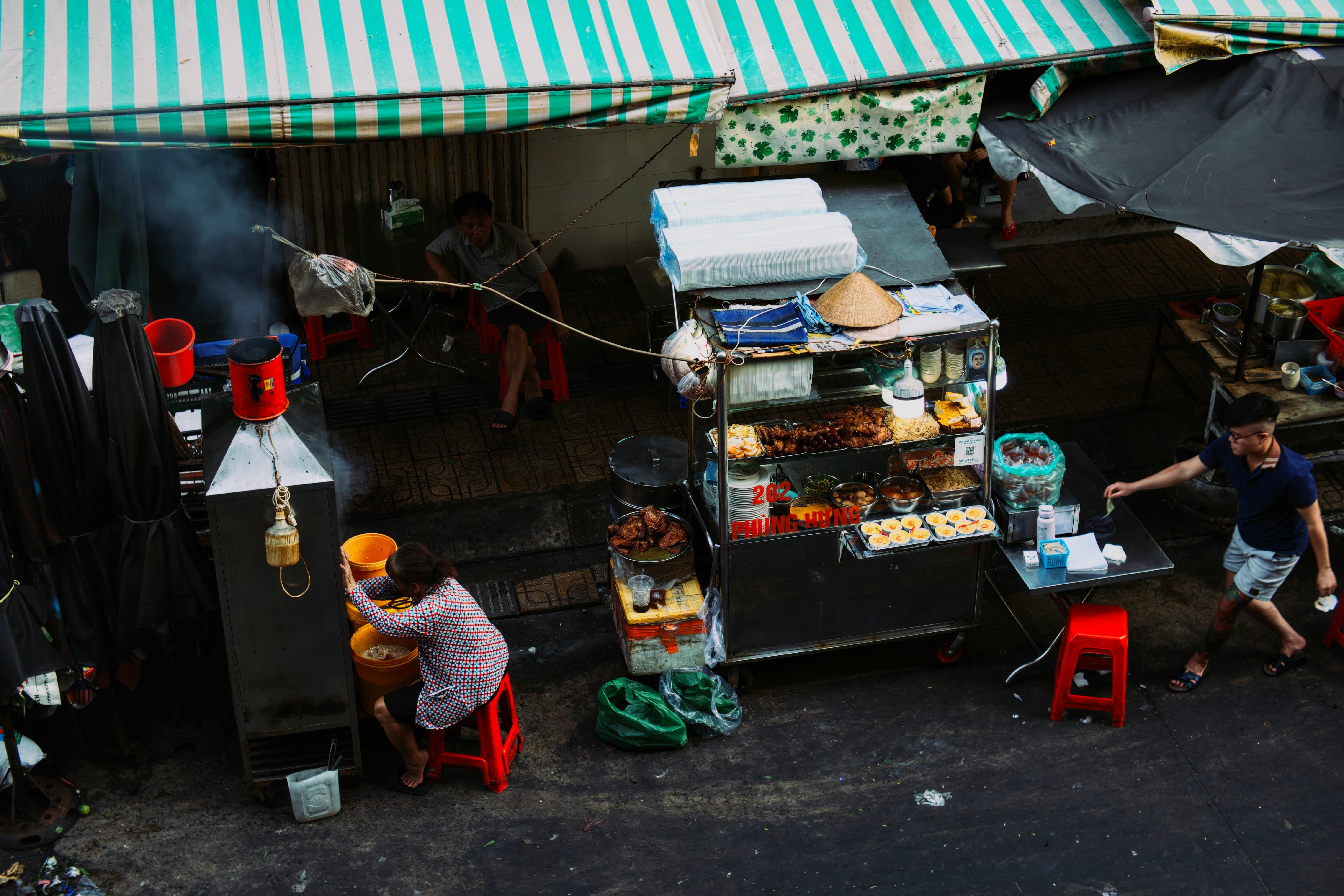 Δωρεάν Ένας πολυσύχναστος πάγκος με street food σε μια αστική αγορά που παρουσιάζει την τοπική κουζίνα και τη ζωή στο δρόμο. Φωτογραφία από στοκ φωτογραφιών