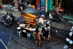 Two women preparing food at a bustling Vietnamese street food stall.