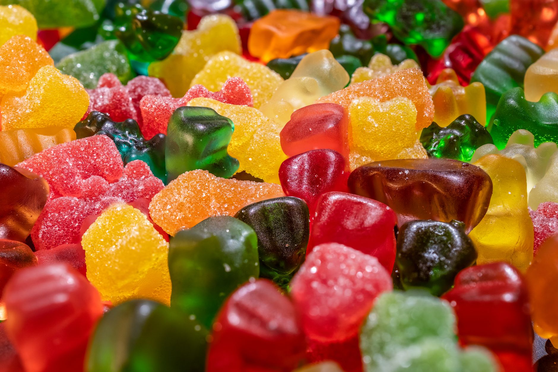 Close-up image of vibrant gummy bears covered in sugar for a sweet treat.
