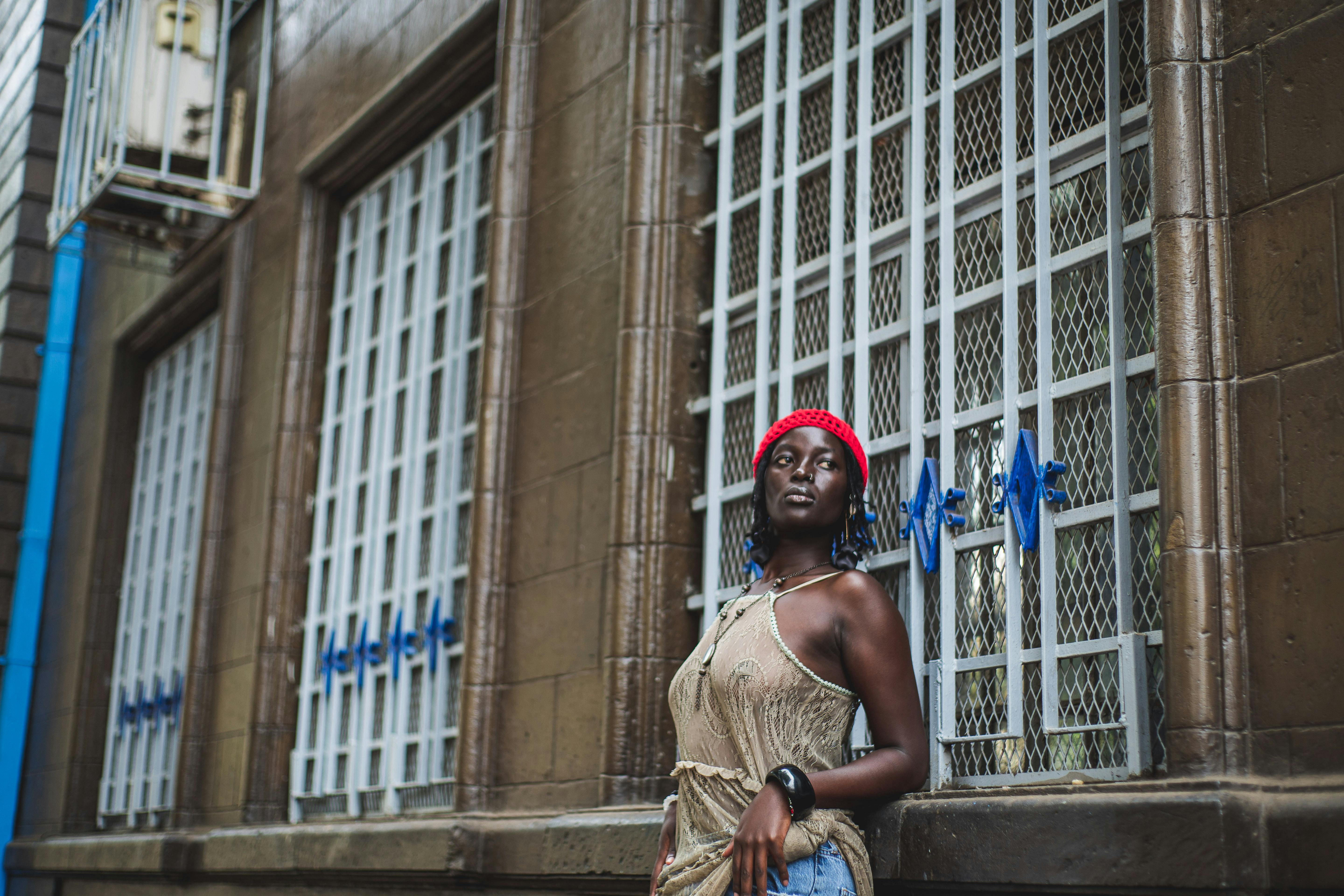 Gratis Potret seorang wanita berbaret merah bersandar di sebuah bangunan di Nairobi, Kenya. Foto Stok