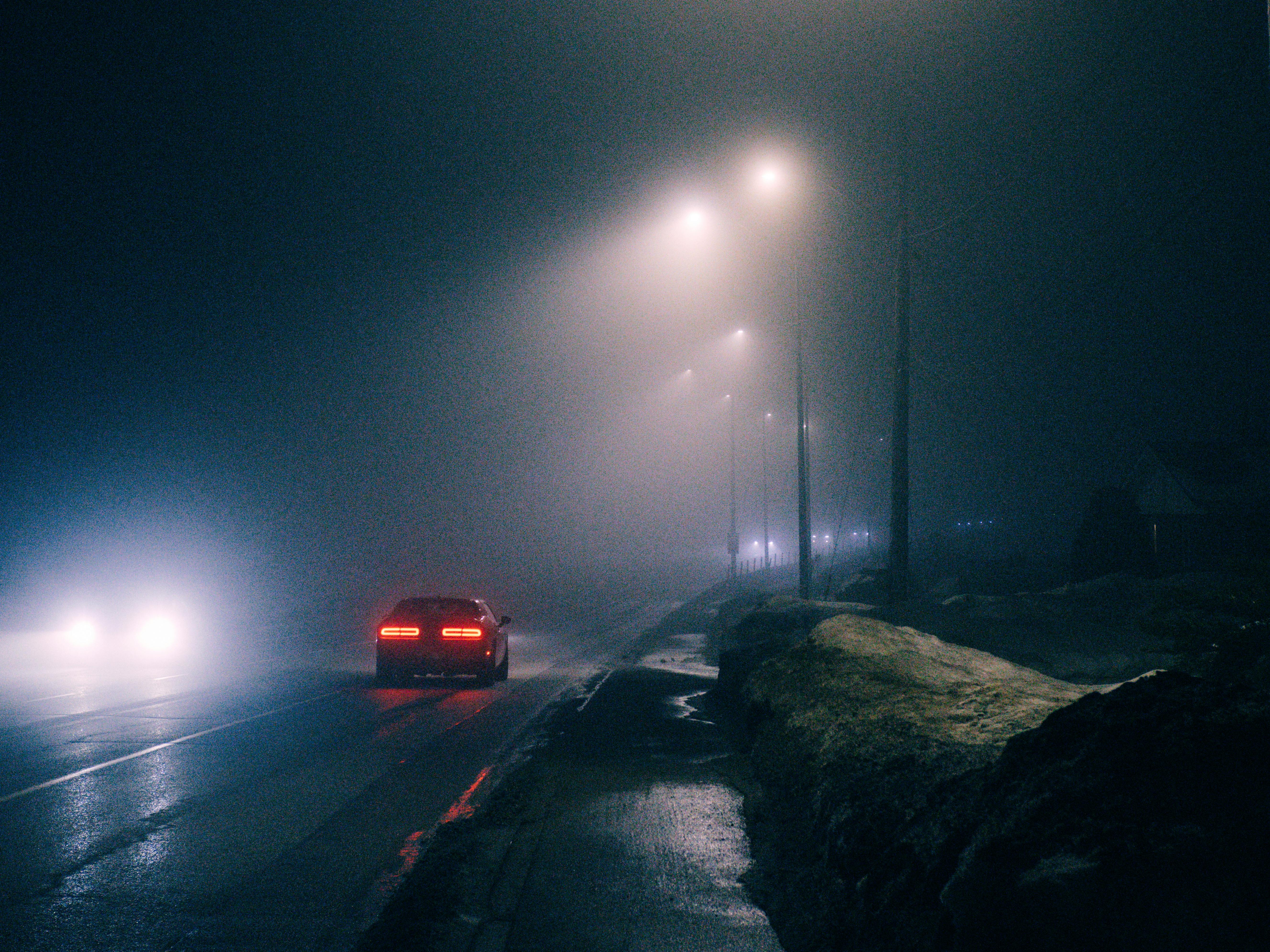 Gratis Pemandangan malam berkabut di Kingston, Ontario, dengan lampu depan mobil menerangi jalan yang sepi. Foto Stok