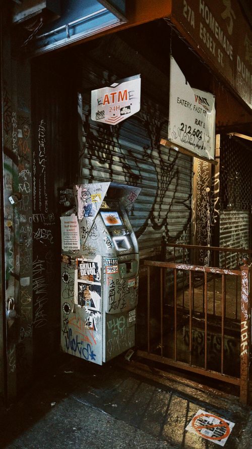 Free A gritty urban street scene with a graffiti-covered ATM at night in New York City. Stock Photo