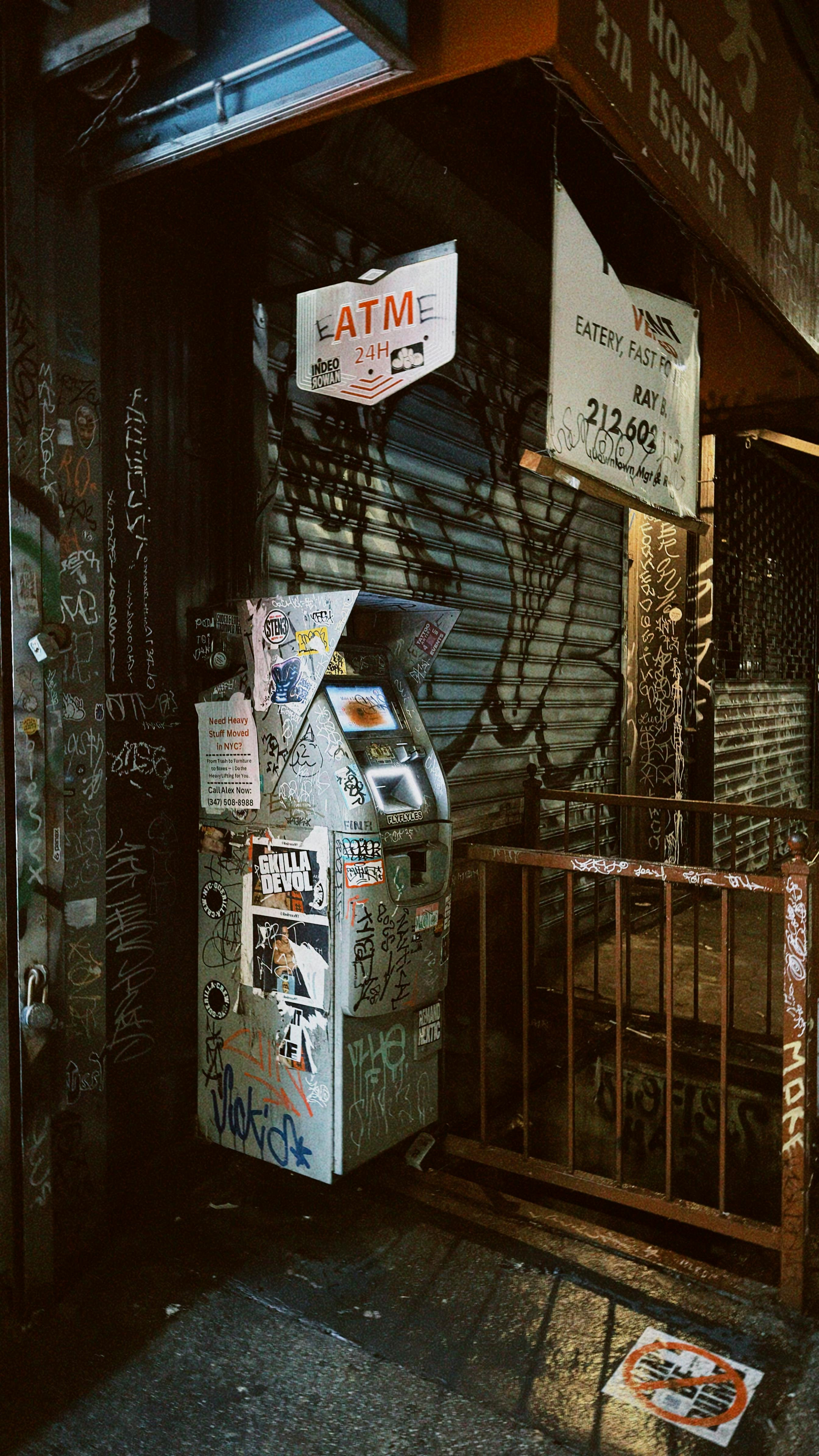 Gratis Una cruda scena di strada urbana con un bancomat ricoperto di graffiti di notte a New York City. Foto a disposizione