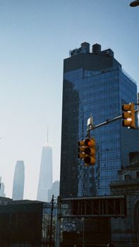 Urban street view featuring NYC skyscrapers and a traffic light under a clear blue sky.