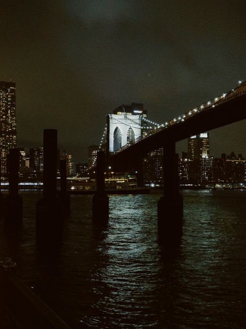 Free A stunning nighttime shot of the Brooklyn Bridge in New York City, illuminated against the skyline. Stock Photo