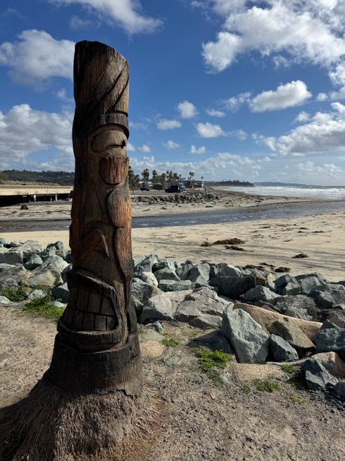 Free A wooden totem pole overlooking a rocky beach in Encinitas, CA, under a blue sky. Stock Photo