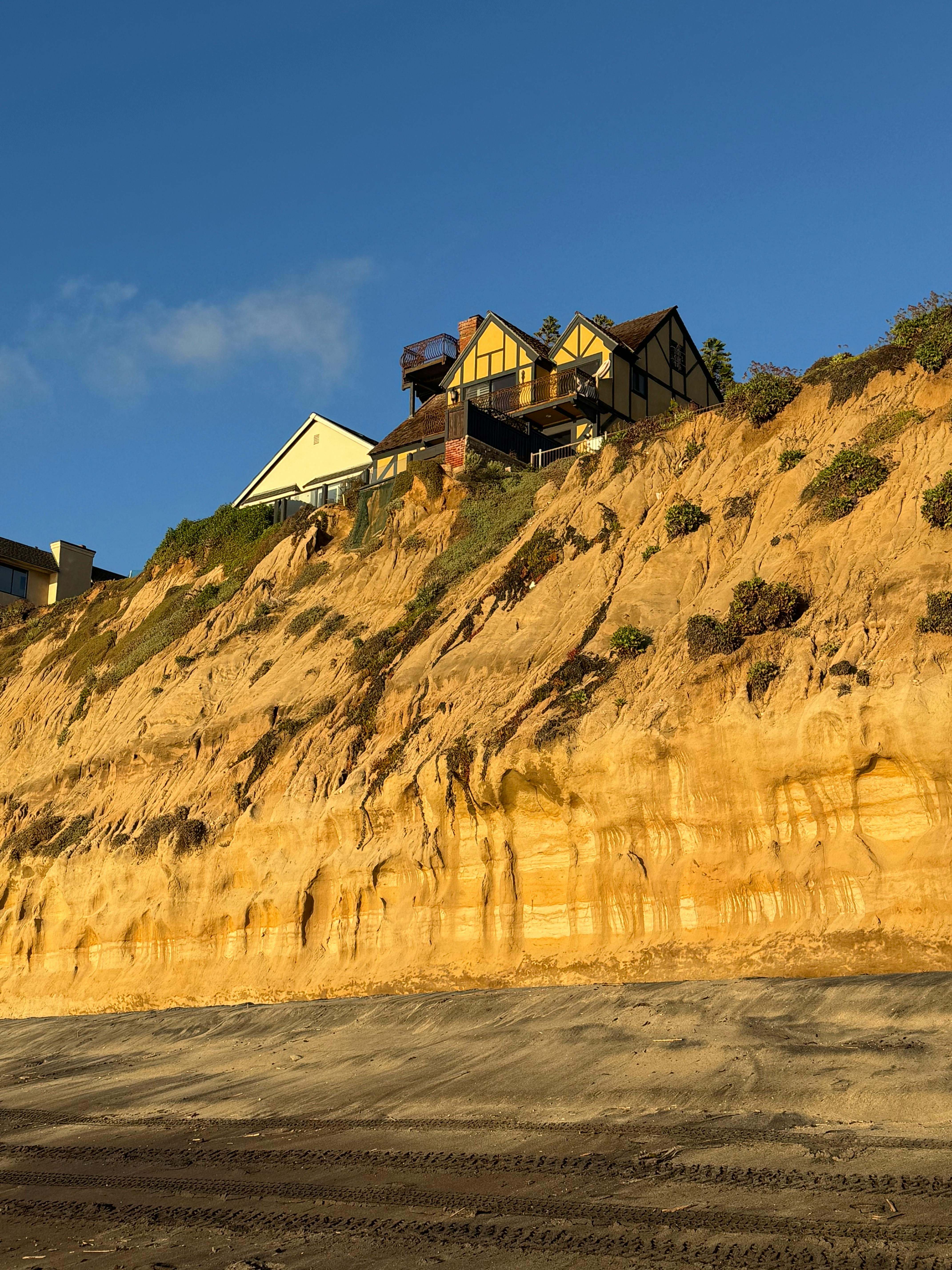 Kostenlos Wunderschöner Blick auf die auf Klippen thronenden Häuser in Encinitas, Kalifornien, während des Sonnenuntergangs, der atemberaubende Erosionsmuster offenbart. Stock-Foto