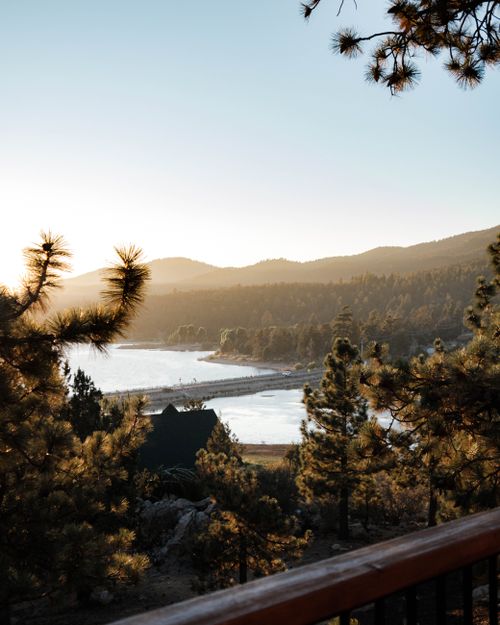Free A tranquil sunrise over a lake framed by pine trees creates a serene landscape. Stock Photo