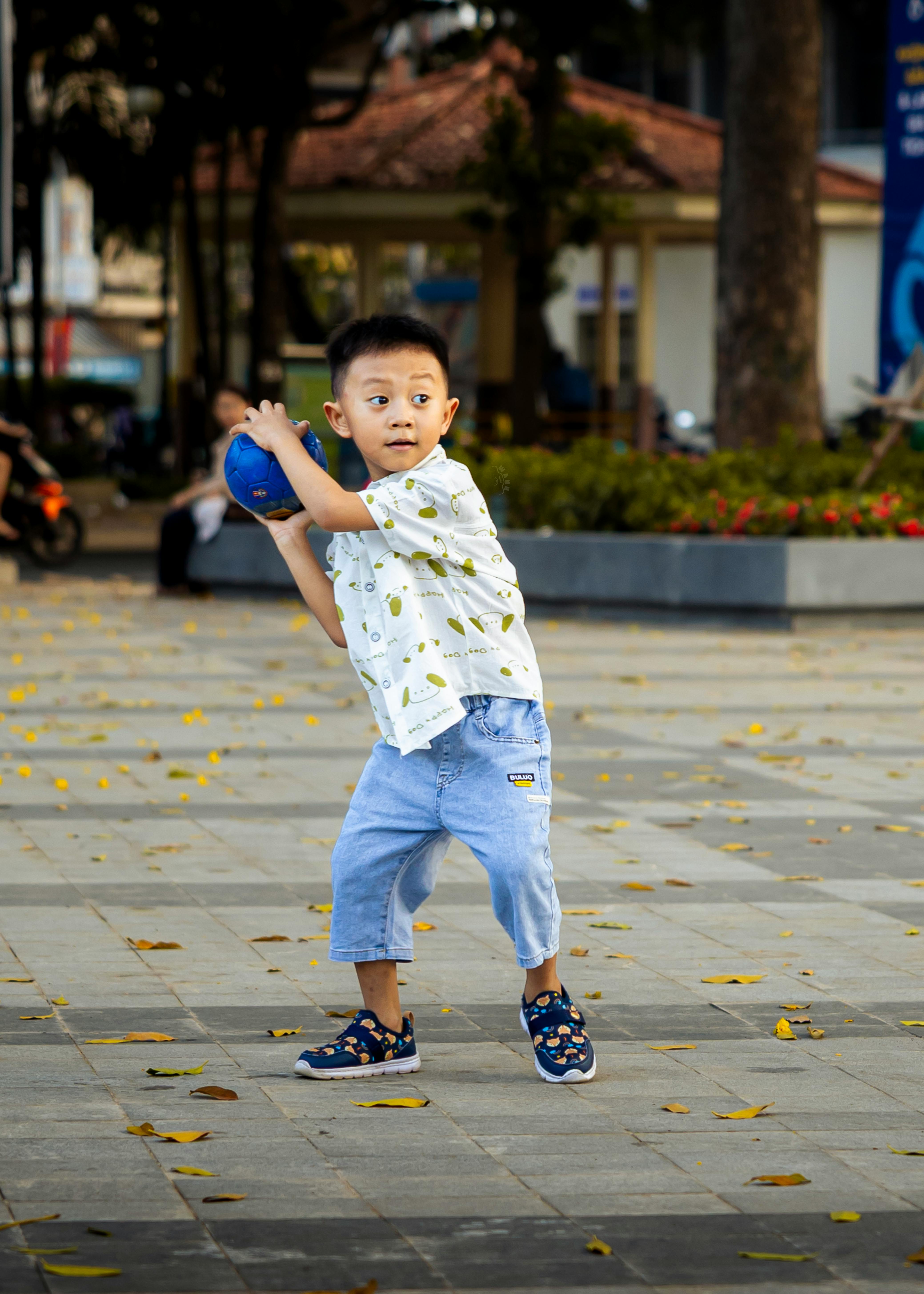 Gratis Seorang anak laki-laki di taman siap melempar bola biru, suasana musim gugur. Foto Stok