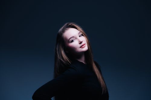 Free Dynamic studio portrait of a confident young woman in dramatic lighting, showcasing elegance and style. Stock Photo