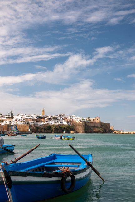 A vibrant view of colorful boats against the historic skyline of Rabat, Morocco.