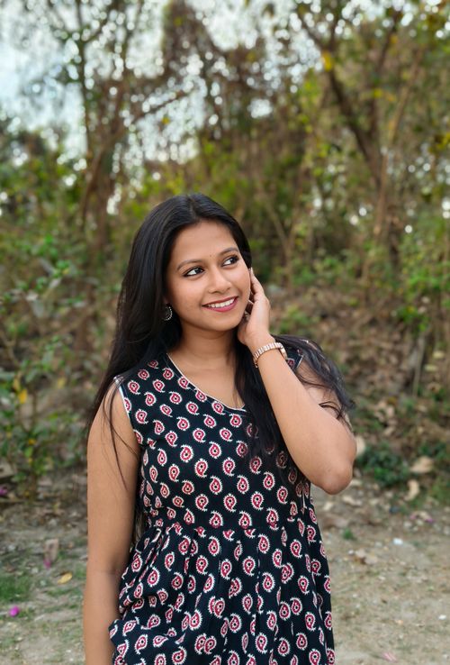 Free Smiling woman in floral dress enjoying a sunny day outdoors in Kolkata. Stock Photo