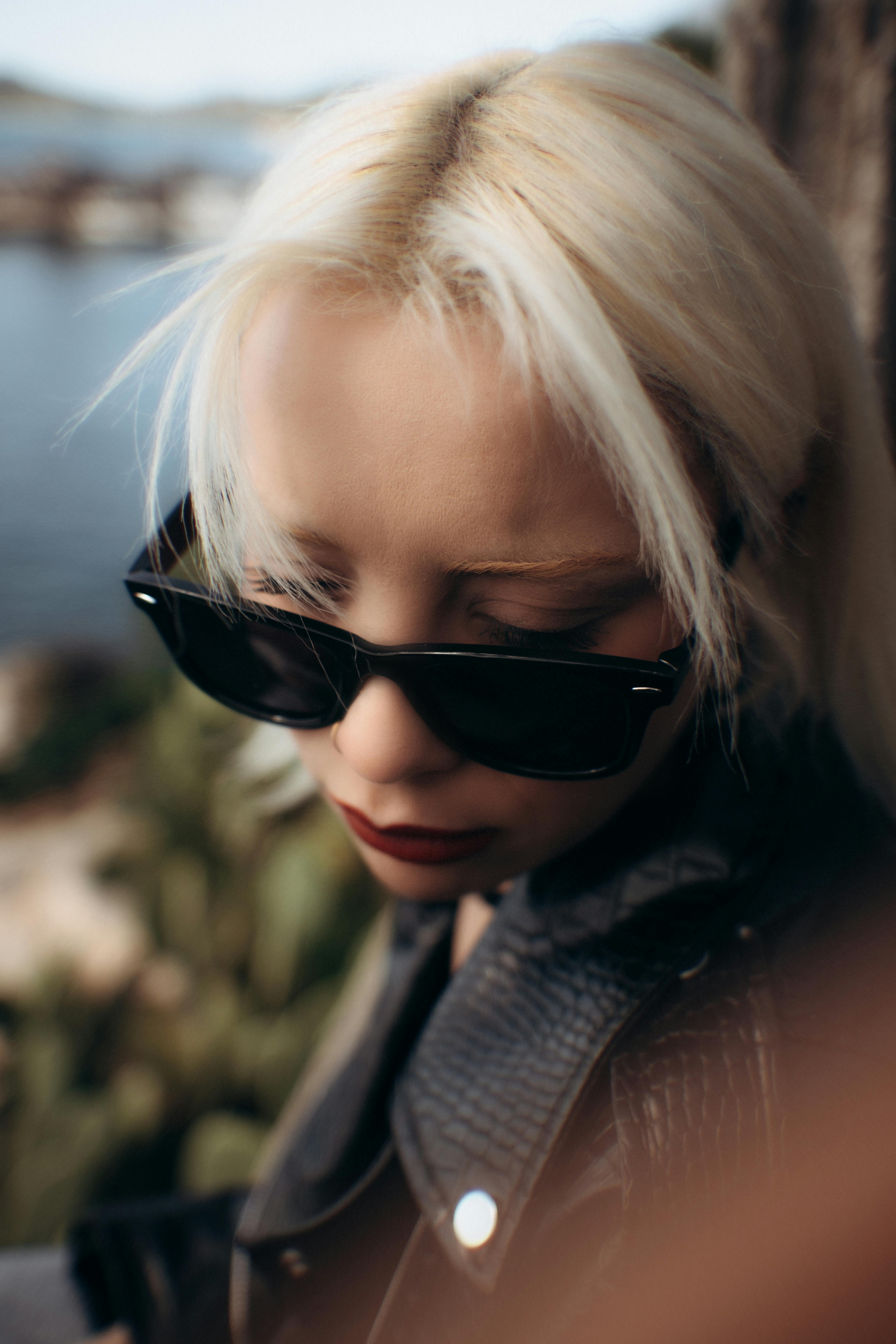 Gratis Moderigtig kvinde med solbriller udendørs nær en smuk sø. Lagerfoto