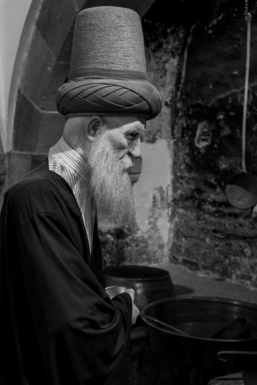 Free Black and white portrait capturing an elderly man in a traditional hat with a somber expression. Stock Photo