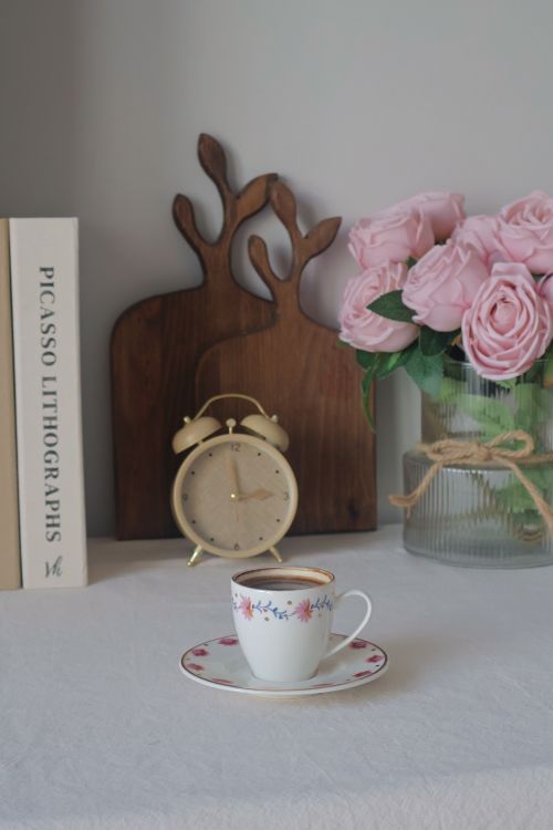 Free A serene morning setup with coffee, pink roses, and art books. Stock Photo