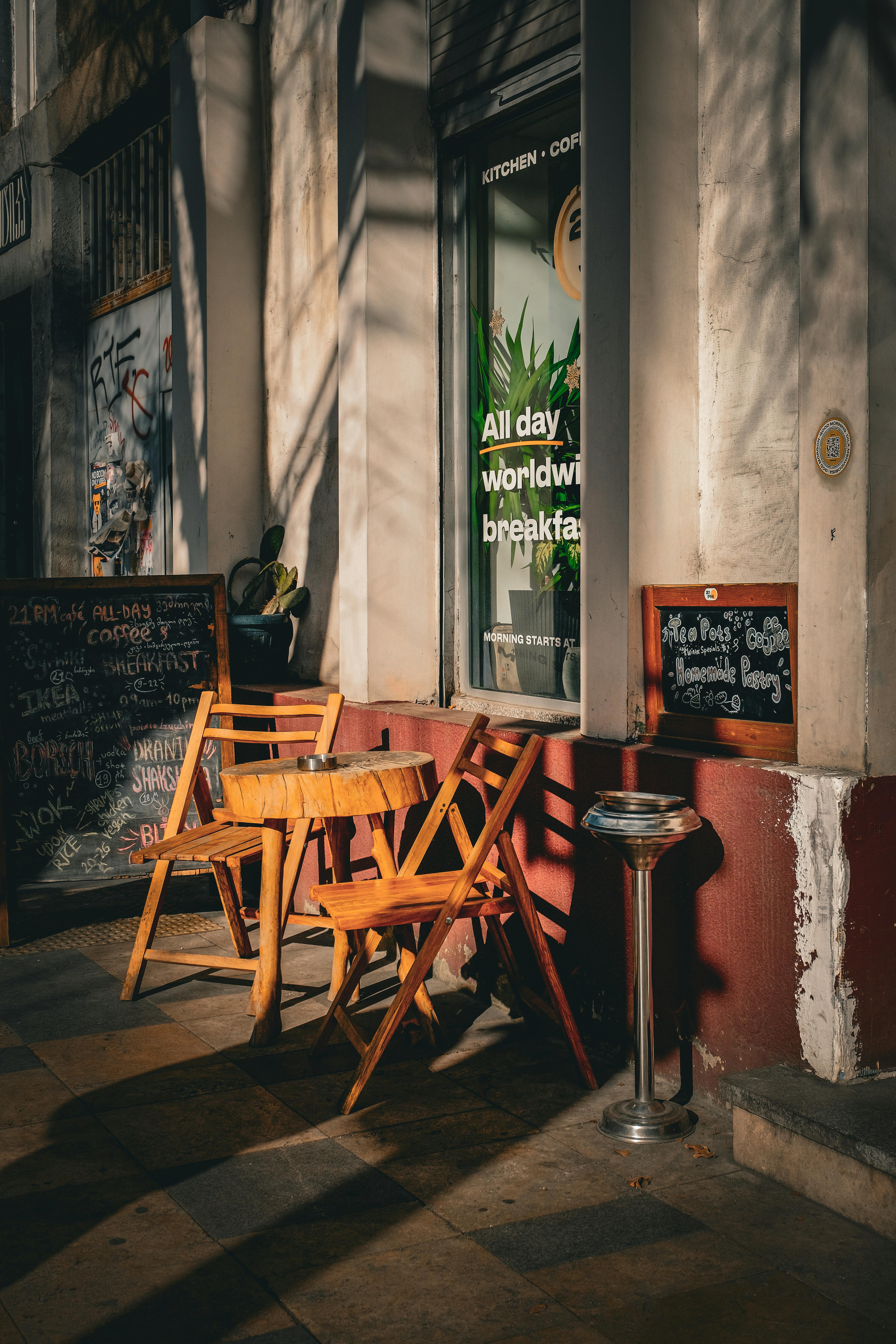 Ücretsiz Sıcak güneş ışığı, Gürcistan'daki bir kahve dükkanının dışındaki şirin bir kafe masasını aydınlatıyor. Stok Fotoğraflar