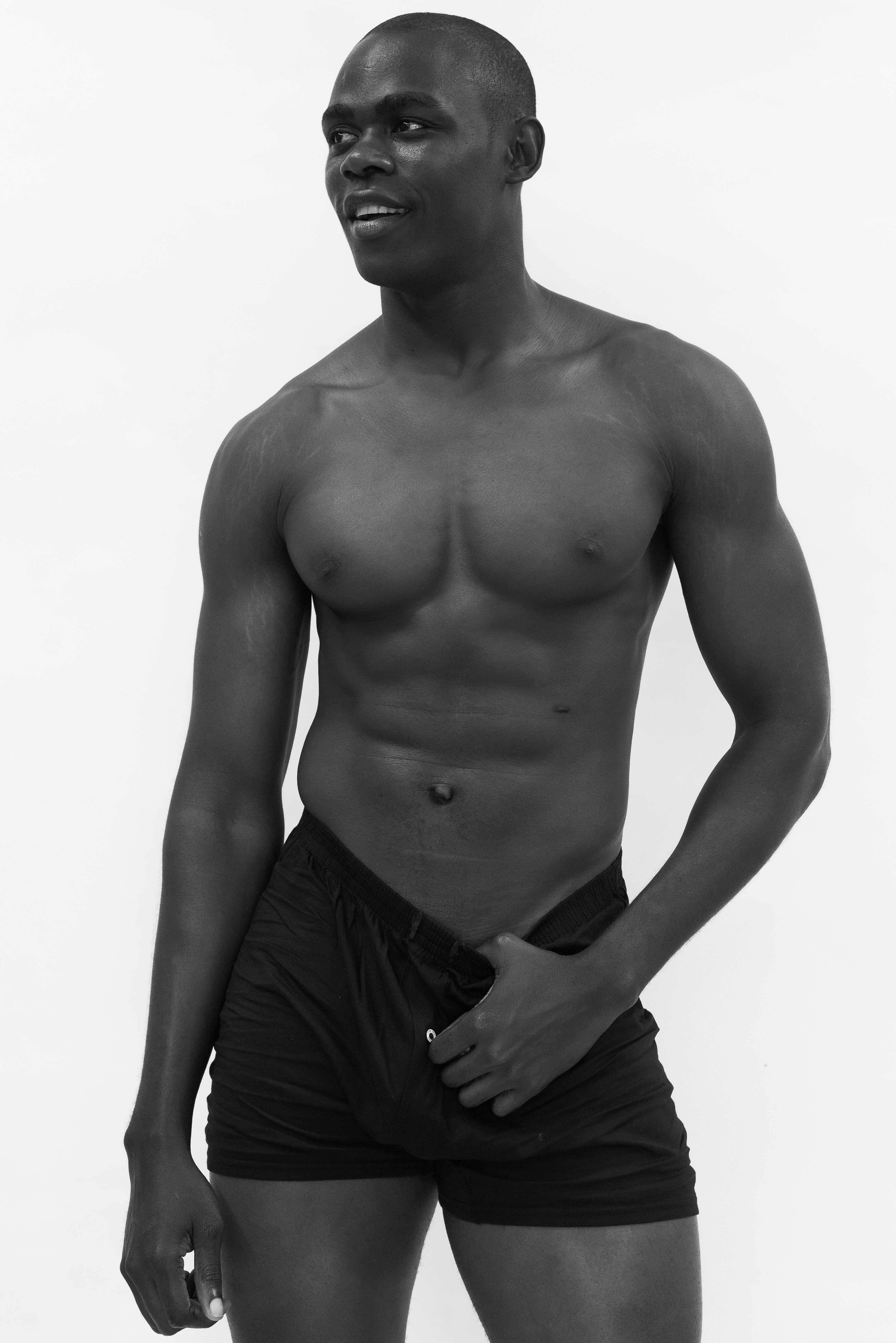 Striking black and white portrait showcasing a fit male model in a minimalist setting.