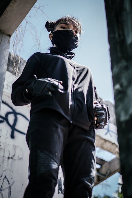 Woman in Black Jacket and Black Pants Standing Near White Wall