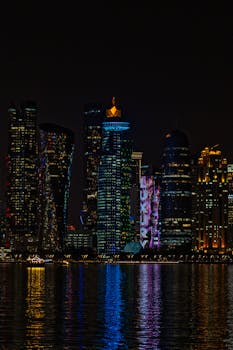 Beautiful night view of Doha's skyline with reflections on the water.