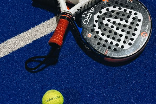Zwei Padelschläger und ein Ball auf dem blauen Platz