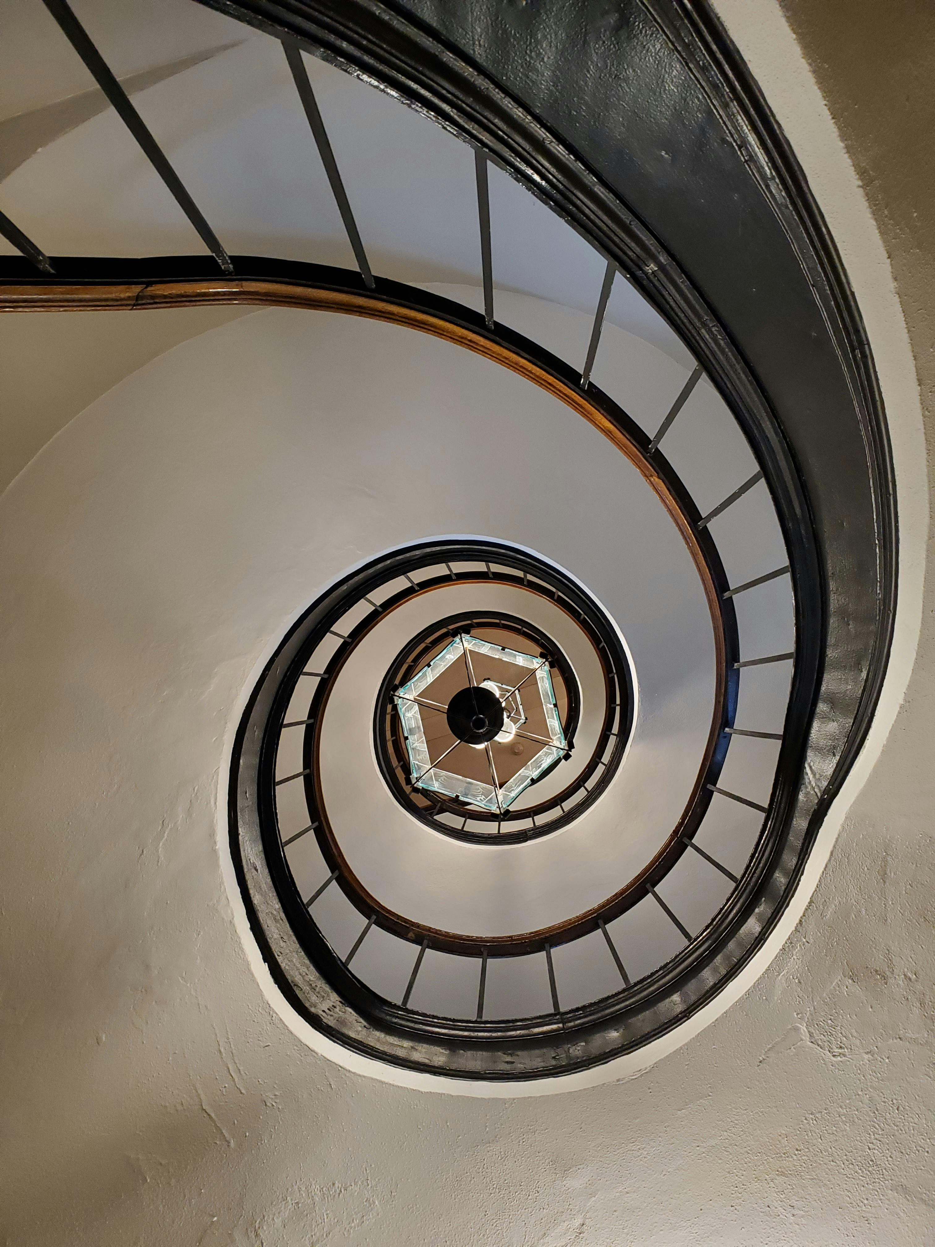 бесплатная Потрясающий вид на винтовую лестницу, демонстрирующую элегантные изгибы и минималистичный дизайн. Стоковое фото
