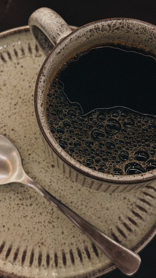 Free Close-up shot of a black coffee in a rustic ceramic cup with saucer. Stock Photo