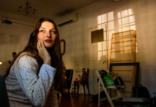 Free A thoughtful woman sitting indoors, bathed in warm sunlight from a window. Stock Photo