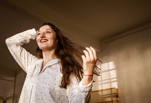 Free A joyful woman with long hair enjoys a sunny morning indoors. Stock Photo
